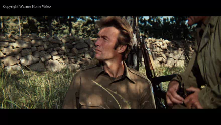HD PC desktop wallpaper/background from the movie Kelly's Heroes: a World War II soldier in olive uniform sits by a stone wall with a rifle, gazing upward in sunlit grass.