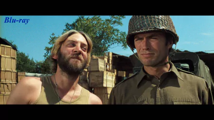 HD PC desktop wallpaper background from the movie Kelly's Heroes: two WWII soldiers—a bearded man smiling and a helmeted soldier—stand before stacked wooden crates under a blue sky.