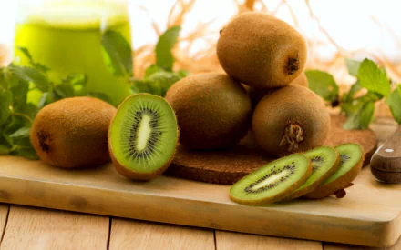 HD PC desktop wallpaper and background featuring fresh food: whole and sliced kiwis on a wooden cutting board with green juice and leafy garnish in soft natural light.