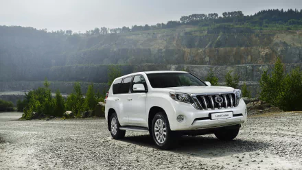 2014 Toyota Land Cruiser white SUV parked on gravel with rocky hills in the background, featured as an HD PC desktop wallpaper.