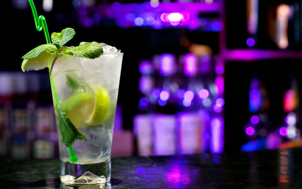 HD desktop wallpaper featuring a refreshing mojito cocktail with lime, mint, and ice against a vibrant, colorful bar background.