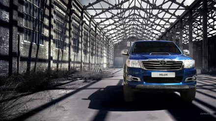 HD PC desktop wallpaper featuring a blue Toyota Hilux parked inside an abandoned industrial warehouse with metal beams and shadow patterns.