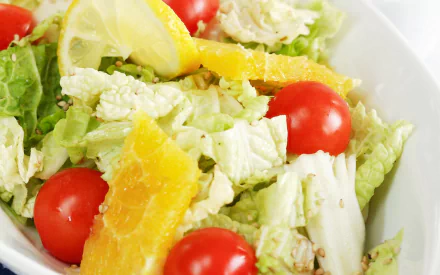 HD PC desktop wallpaper and background of a fresh salad with crisp lettuce, cherry tomatoes, orange slices and a lemon wedge.