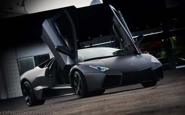 HD PC desktop wallpaper featuring a sleek black Lamborghini Reventon with its scissor doors open, showcasing its sharp, aggressive design.