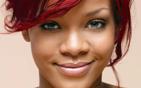 High-definition desktop wallpaper featuring a close-up of Rihanna, showcasing her vibrant red hair and captivating smile against a neutral background.