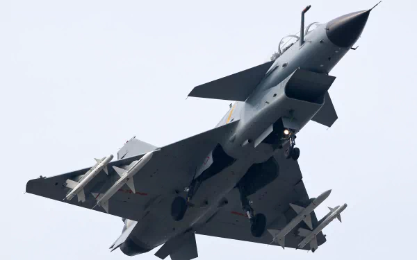 Military Chengdu J-10 fighter jet viewed from below with missiles against pale sky; HD PC desktop wallpaper/background.