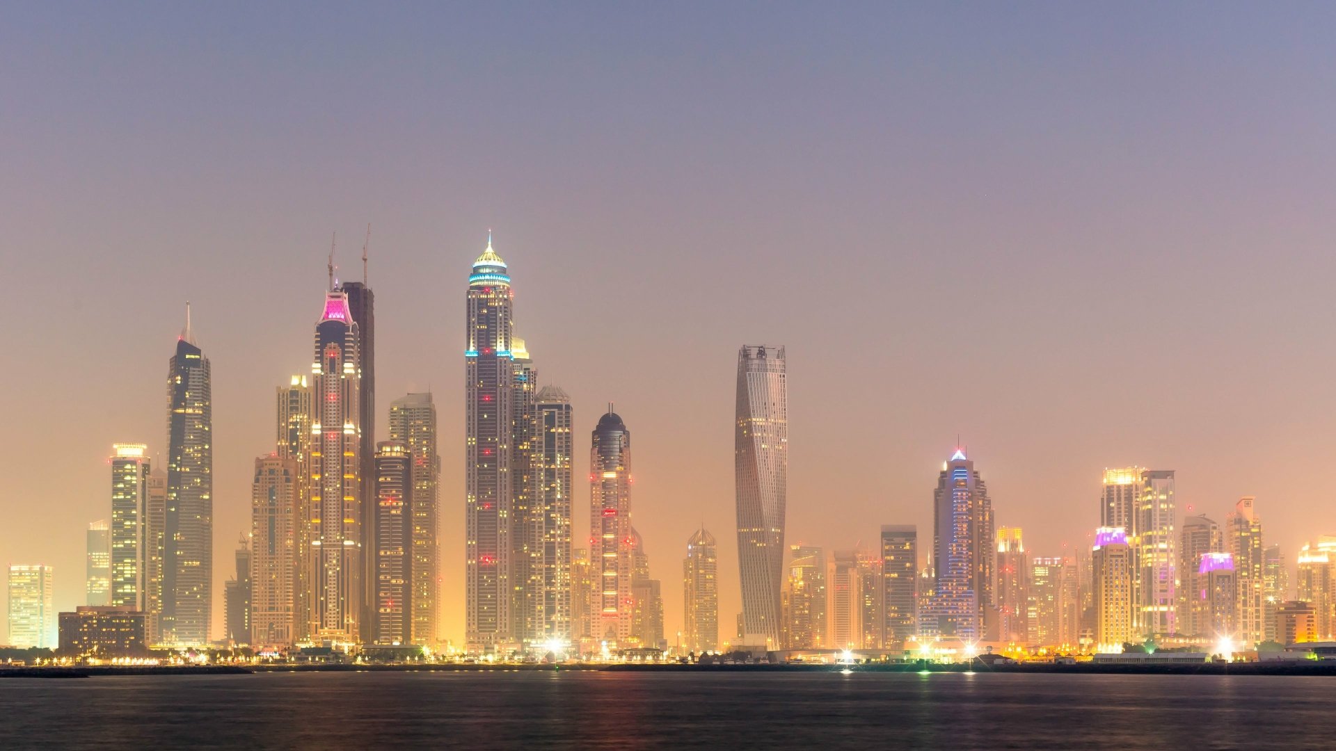 A stunning HD wallpaper showcasing Dubai's iconic skyline at dusk, featuring illuminated skyscrapers that reflect the city's modern architecture and vibrant atmosphere.