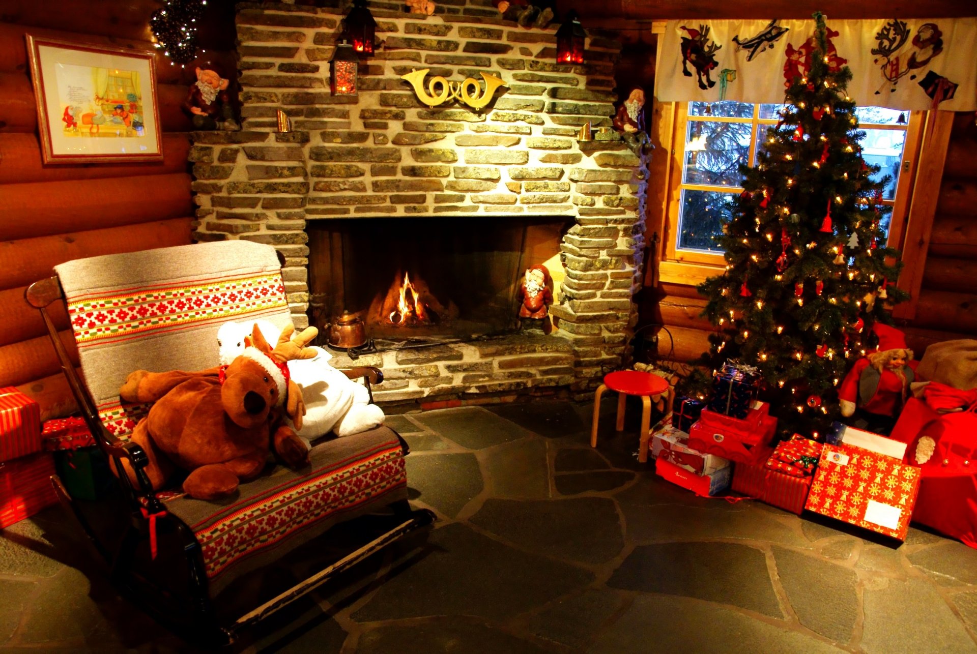A cozy holiday scene featuring a stone fireplace, a stuffed animal, a beautifully decorated Christmas tree, and wrapped gifts, creating a warm atmosphere for Christmas celebrations.