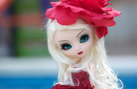 A close-up of a beautifully designed doll with long blonde hair and striking blue eyes, adorned with a vibrant red flower. This HD image serves as an engaging desktop wallpaper.