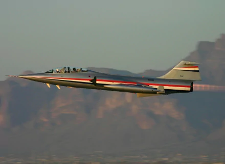 Military Lockheed F-104 Starfighter soaring above desert mountains, HD PC desktop wallpaper and background.