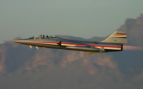 Military Lockheed F-104 Starfighter soaring above desert mountains, HD PC desktop wallpaper and background.