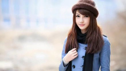 HD desktop wallpaper featuring a Korean woman dressed in a blue coat, black scarf, and brown hat, standing outdoors against a blurred background.