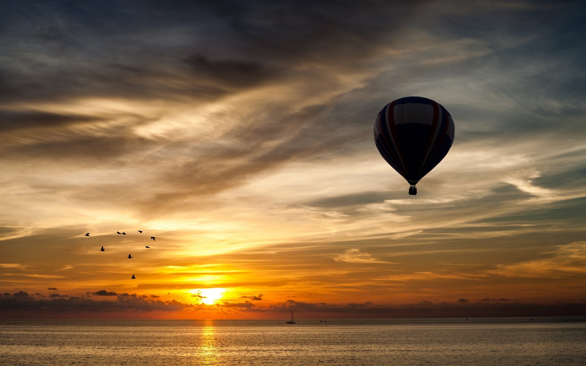 A serene hot air balloon floats above a tranquil sea at sunset, with vibrant colors in the sky, creating a stunning HD desktop wallpaper for nature enthusiasts.