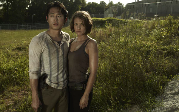 An 8K Ultra HD desktop wallpaper featuring two characters from the TV show The Walking Dead standing in a grassy, sunlit area near a fence.