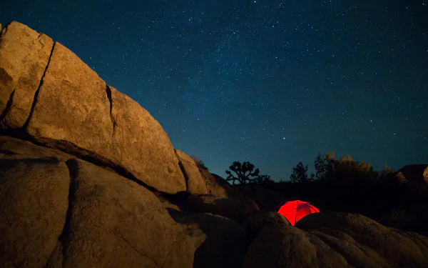 4K Ultra HD sci-fi inspired PC desktop wallpaper showing a glowing red tent nestled among large rocks under a star-filled night sky.