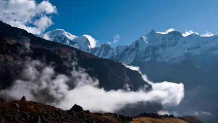 4K Ultra HD desktop wallpaper showcasing the majestic Himalayan mountains with clear blue skies, rugged peaks, and drifting clouds enveloping the natural landscape.