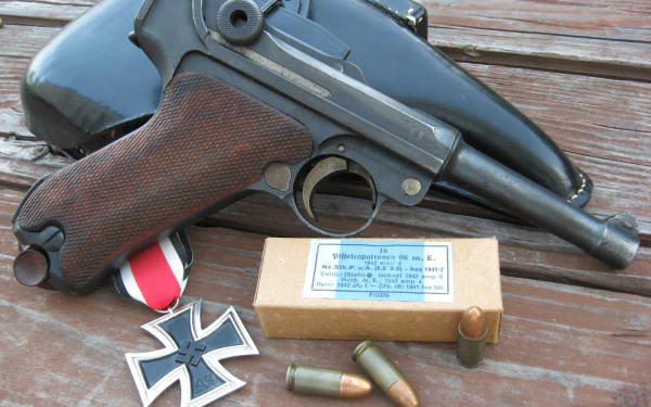 HD PC desktop wallpaper showing a man-made Luger pistol with holster, spare rounds and military medals arranged on a weathered wooden surface