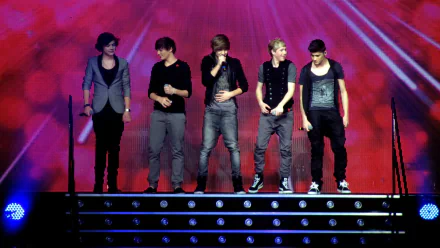 A high-definition wallpaper featuring the musical group One Direction performing on stage, with vibrant lights and a dynamic atmosphere.