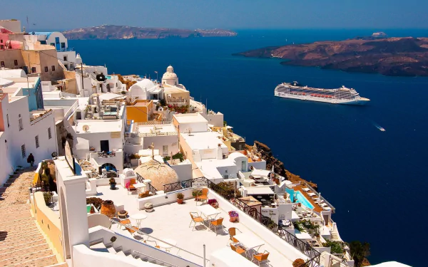 A scenic view of Santorini showcasing its iconic white buildings overlooking the blue sea, with a cruise ship sailing in the distance. A vibrant HD desktop wallpaper and background.