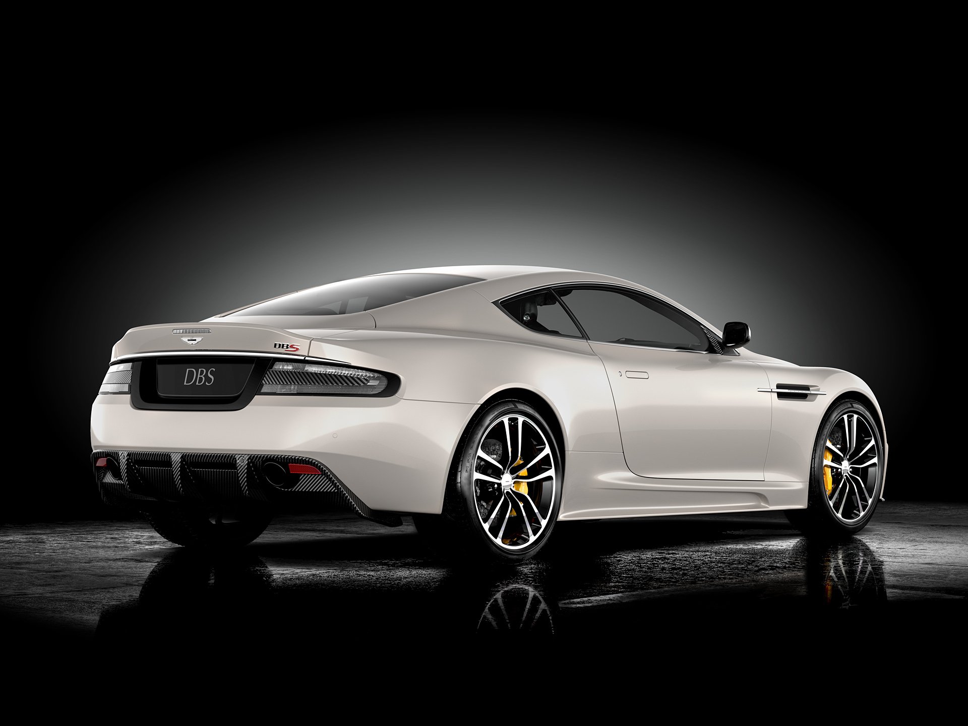 Aston Martin DBS showcased in a sleek silver finish, captured in a high-definition PC desktop wallpaper with a dark gradient background highlighting the vehicle's design.