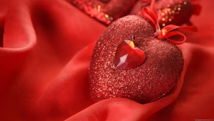 Artistic HD PC desktop wallpaper featuring a sparkling red heart with a gemstone center resting on rich red fabric.
