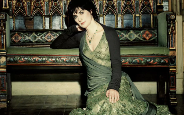 HD PC desktop wallpaper of a music singer in a flowing green gown seated on an ornate wooden bench, moody lighting and Celtic‑inspired atmosphere.