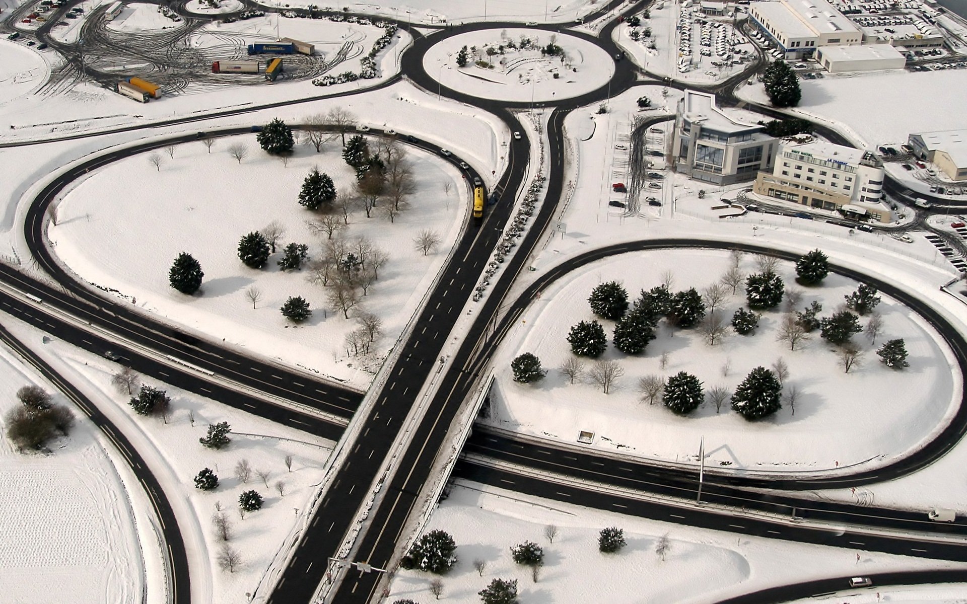 HD PC desktop wallpaper and background: aerial view of a snow-covered, man-made highway interchange with roundabouts, trees and buildings in Saint-Malo.