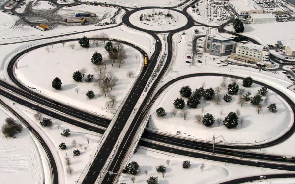 HD PC desktop wallpaper and background: aerial view of a snow-covered, man-made highway interchange with roundabouts, trees and buildings in Saint-Malo.