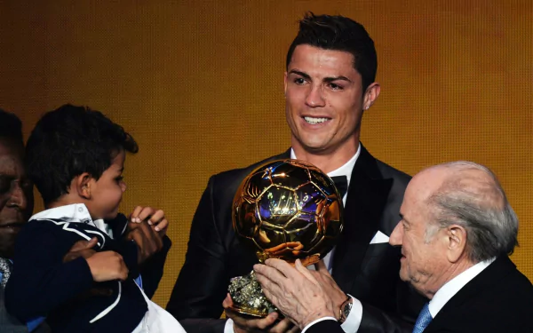 Smiling man in tuxedo holding the Ballon d'Or trophy on stage with officials and a child — Ballon d'Or 2014, Sports HD PC desktop wallpaper background.