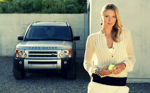 Maria Sharapova stands in front of a silver Land Rover, holding a tennis ball, capturing a sporty and stylish moment in this HD desktop wallpaper.