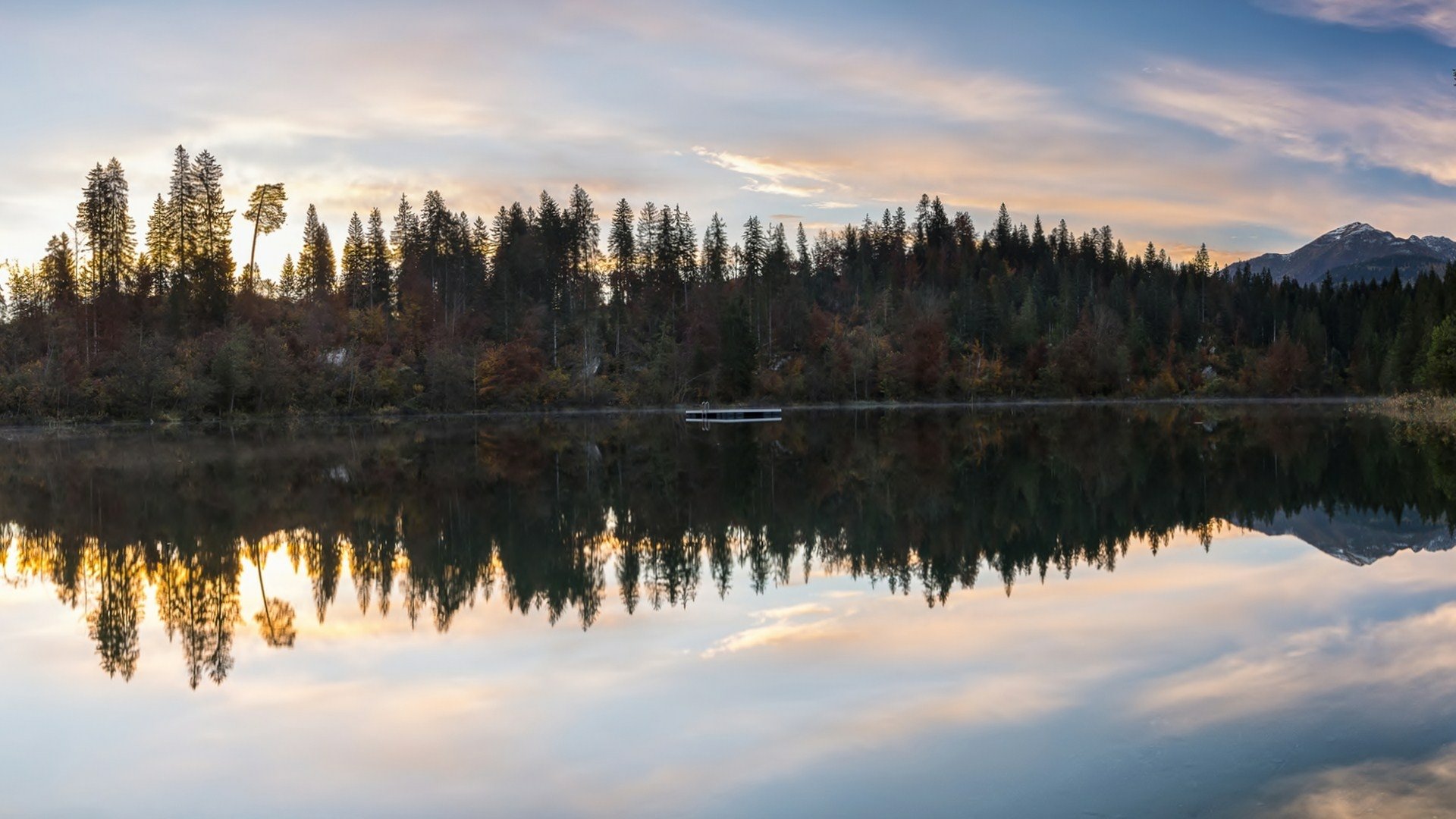 HD PC desktop wallpaper and background — nature scene of pine forest and distant mountain at sunrise, mirror-like reflection on a calm lake.