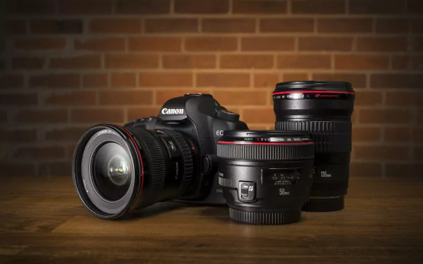 A Canon camera with two lenses is displayed on a wooden surface, set against a brick background, capturing a sleek, man-made design in stunning 4K Ultra HD resolution.