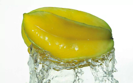 HD PC desktop wallpaper: glossy yellow Starfruit slice splashing through water, fresh fruit food close-up on white background.