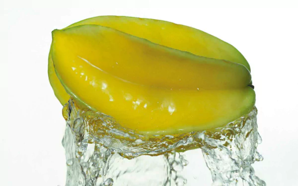 HD PC desktop wallpaper: glossy yellow Starfruit slice splashing through water, fresh fruit food close-up on white background.