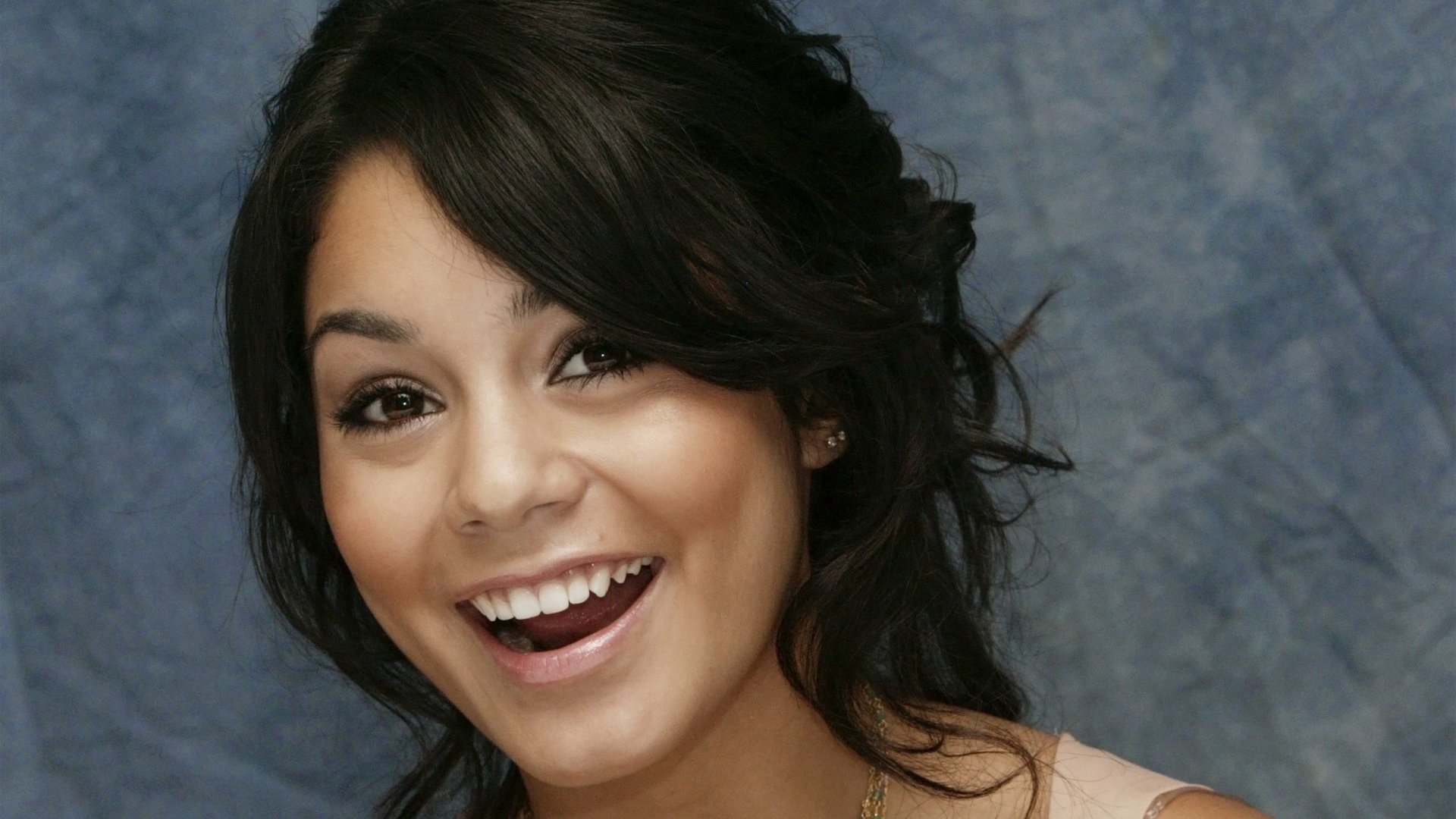 HD desktop wallpaper featuring a close-up of celebrity Vanessa Hudgens smiling against a soft blue-gray background.