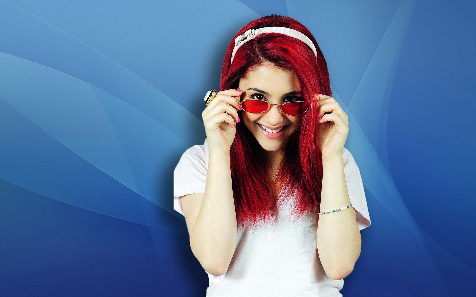 Ariana Grande smiles playfully, wearing sunglasses with her vibrant red hair. The HD desktop wallpaper features a smooth blue background, adding a cool vibe.