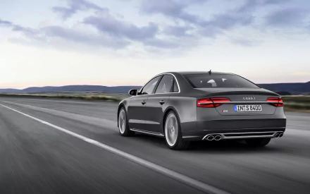 A sleek Audi A8 drives along an open road, showcasing its elegant design against a backdrop of expansive skies. This HD image serves as a stunning desktop wallpaper.