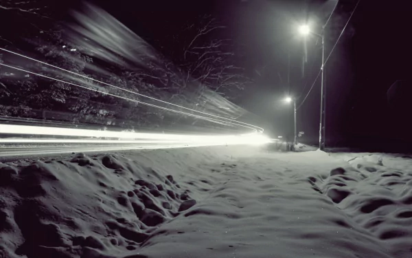 Time-lapse photography HD PC desktop wallpaper: snowy roadside at night with streaking car light trails and glowing street lamps.