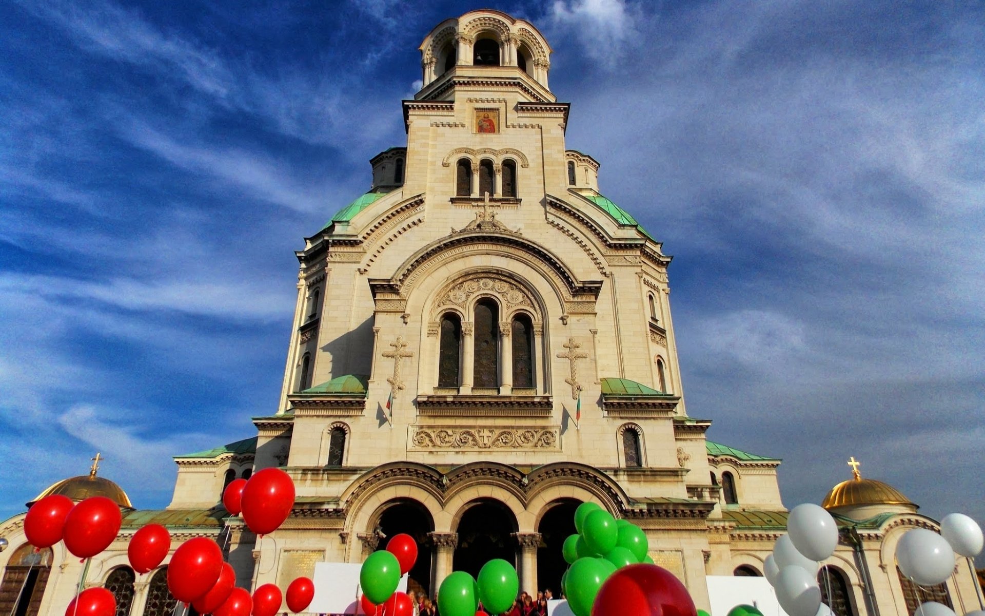 HD PC desktop wallpaper: Alexander Nevsky Cathedral's ornate facade beneath a vivid blue sky, framed by red, green and white balloons — religious landmark.