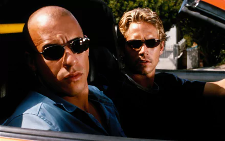 Vin Diesel as Dominic Toretto and Paul Walker as Brian O'Conner pose in a car, embodying the spirit of speed and camaraderie from The Fast and The Furious. HD desktop wallpaper.
