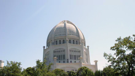 HD desktop wallpaper featuring the white dome of a Baha'i Temple surrounded by greenery under a clear sky, highlighting its religious architecture.