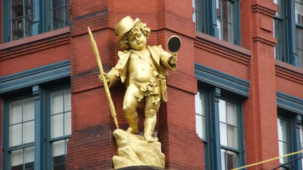 Man-made golden cherub statue mounted on a red-brick building corner, photographed as an HD PC desktop wallpaper and background.