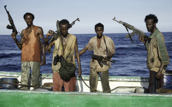 HD wallpaper from Captain Phillips featuring four individuals on a boat with the ocean in the background.