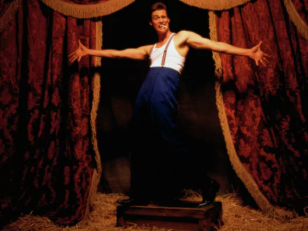 HD desktop wallpaper featuring a man in a comedic pose with wide arms, standing between red curtains, reminiscent of Jim Carrey's expressive style.