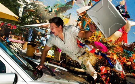 Mark Wahlberg as Daniel Lugo bursts into action in this vibrant scene from the movie Pain & Gain, featuring dynamic splashes of color and high-energy movement.