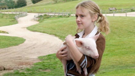 Dakota Fanning as Fern in Charlotte's Web (2006), cradling a piglet in a serene farm setting, capturing the essence of friendship and childhood in this heartwarming tale.