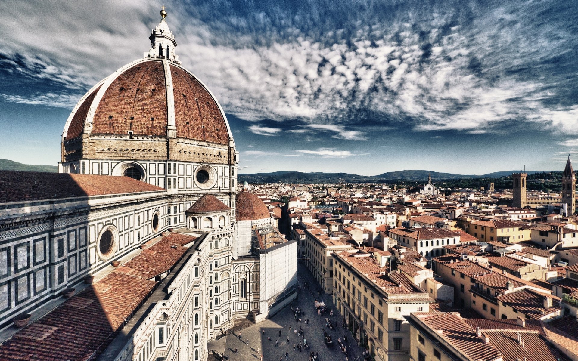 HD PC desktop background showing the Basilica of Saint Mary of the Flower (Florence Duomo) dominating a cityscape under dramatic clouds, a religious landmark and historic cathedral viewed from above.
