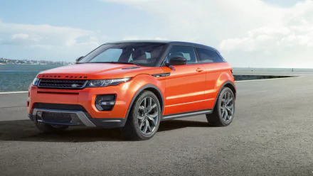 2015 Range Rover Evoque Autobiography in orange parked by the waterfront, captured in a high-definition desktop wallpaper showcasing the vehicle’s sleek design.