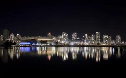 HD wallpaper featuring a stunning night view of Vancouver, Canada with city lights reflecting on the calm water, highlighting the city's modern architecture.