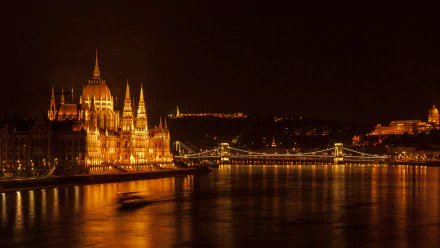 HD wallpaper of Budapest at night, featuring a luminous view of the Hungarian Parliament building and the Chain Bridge over the Danube River.
